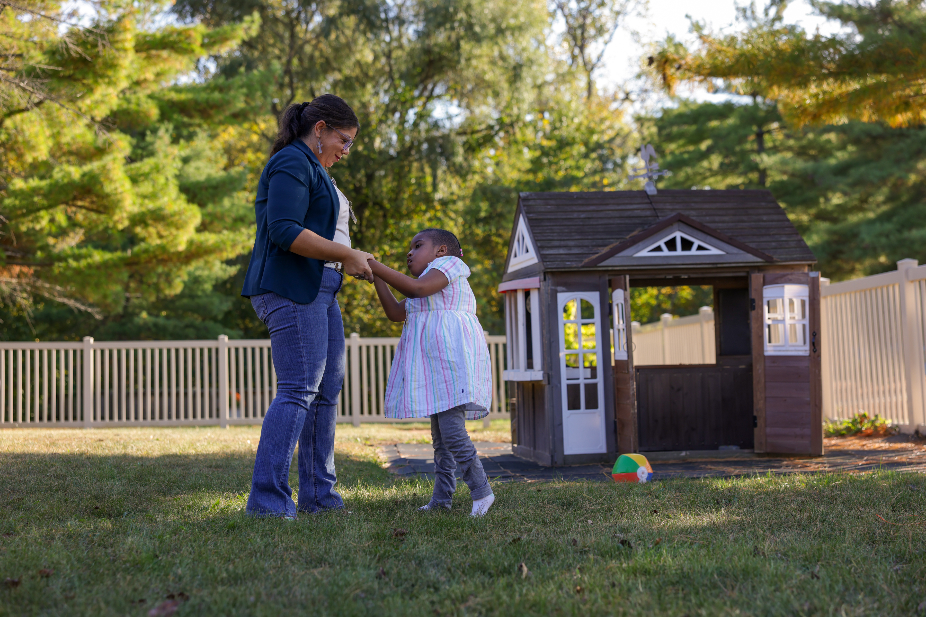 Caregiver helping child with disabilities walk and play outside together.