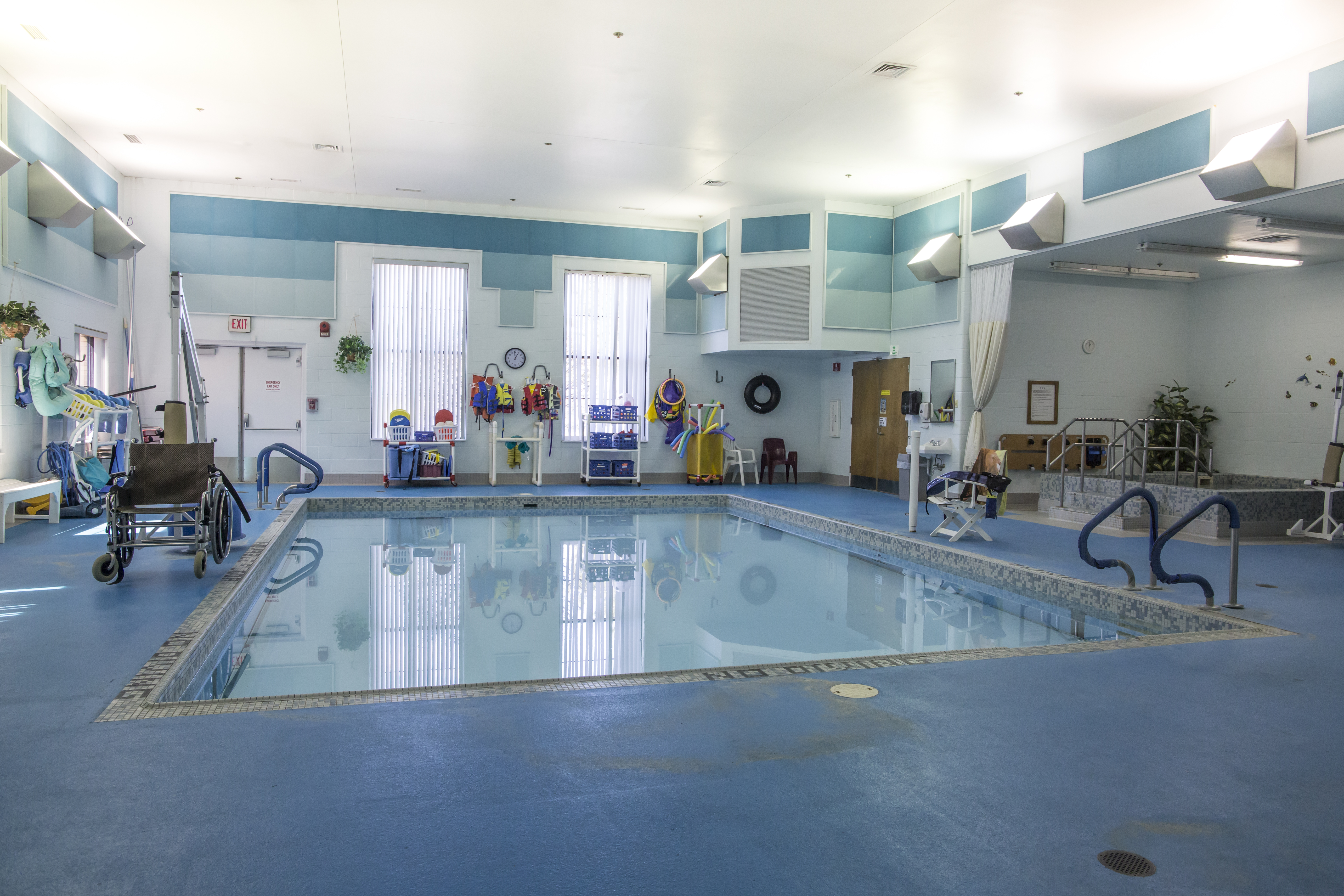 Accessible raised pool with water features and floral-themed flooring at Sunshine Communities.
