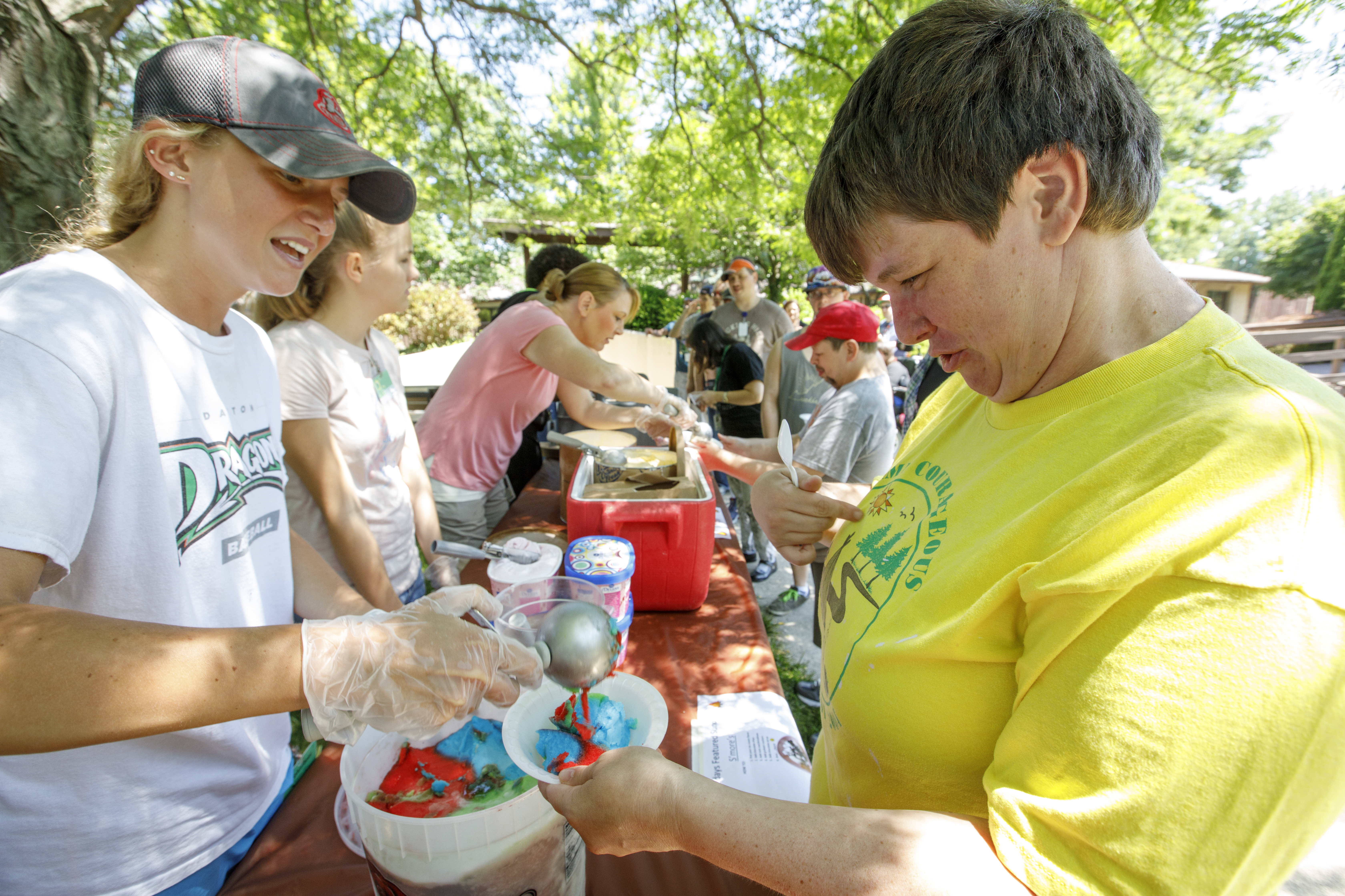 a group of people standing at table scooping ice cream smiling 