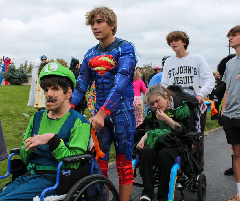 Everyone in costumes, smiling and looking for candy, including a group of people in wheelchairs others are standing 