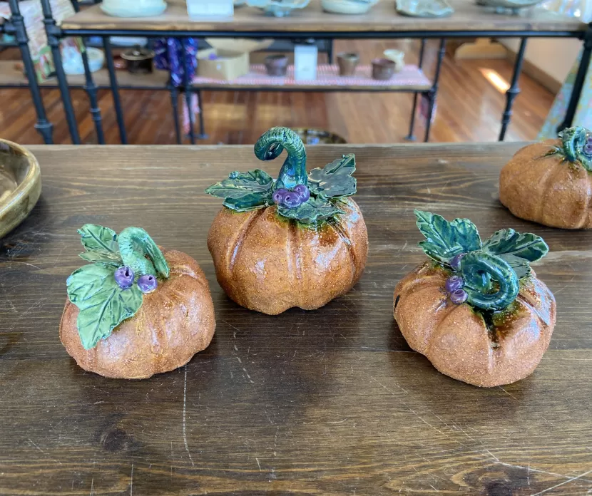 A table with 3 ceramic pumpkins arranged on top.