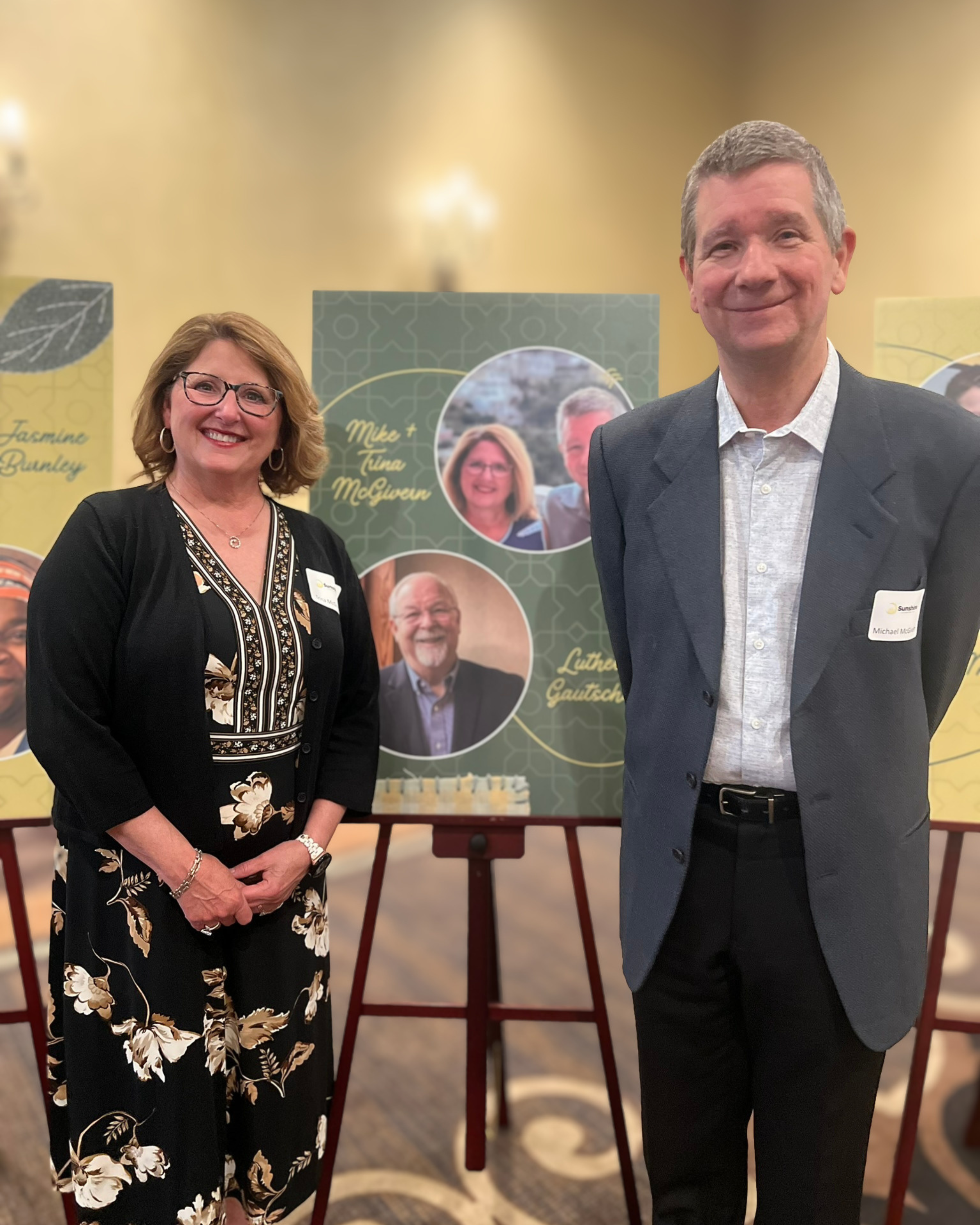 Mike and Trina McGivern standing together at a Sunshine Communities event in front of a display recognizing supporters
