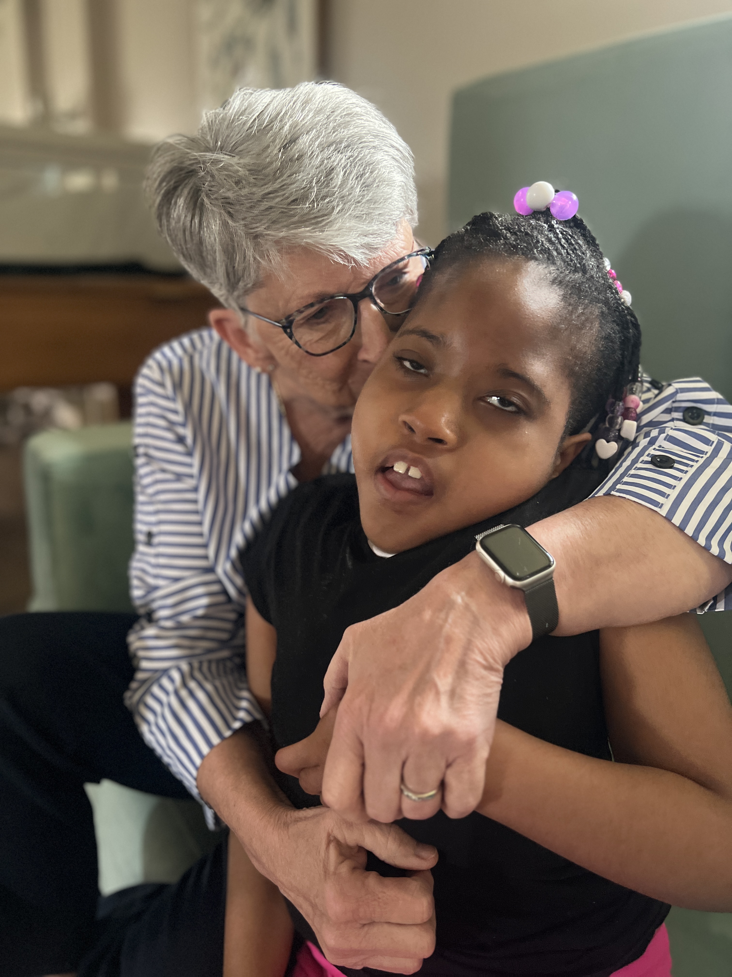 Linda Dittman embraces and kisses Faith on the cheek during a quiet moment together at Sunshine Communities, reflecting the deep compassion and connection that defined her nursing career.
