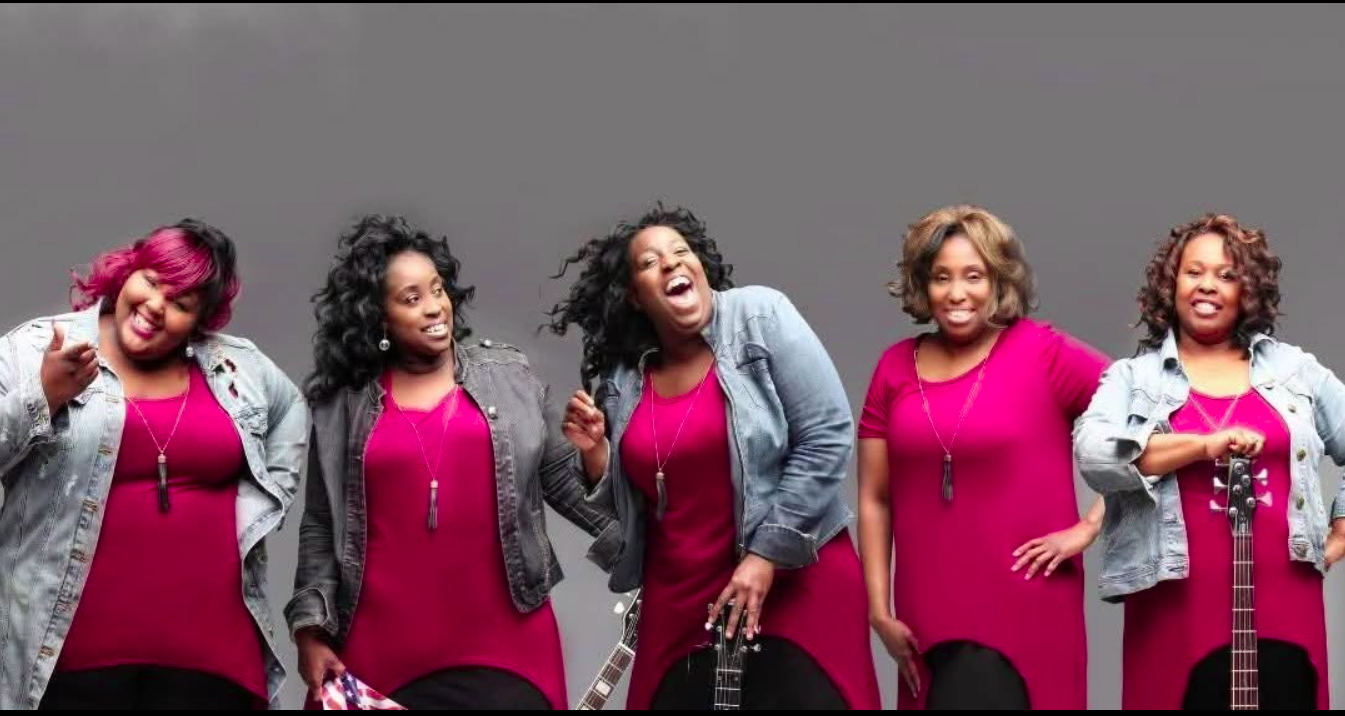Promotional photo of Nikki D and the Sisters of Thunder, a five-member band smiling with guitars, performing at the Sounds of Sunshine Concert Series at Sunshine Communities.