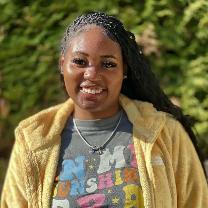 A woman in a t-shirt and zip-up smiling at the camera