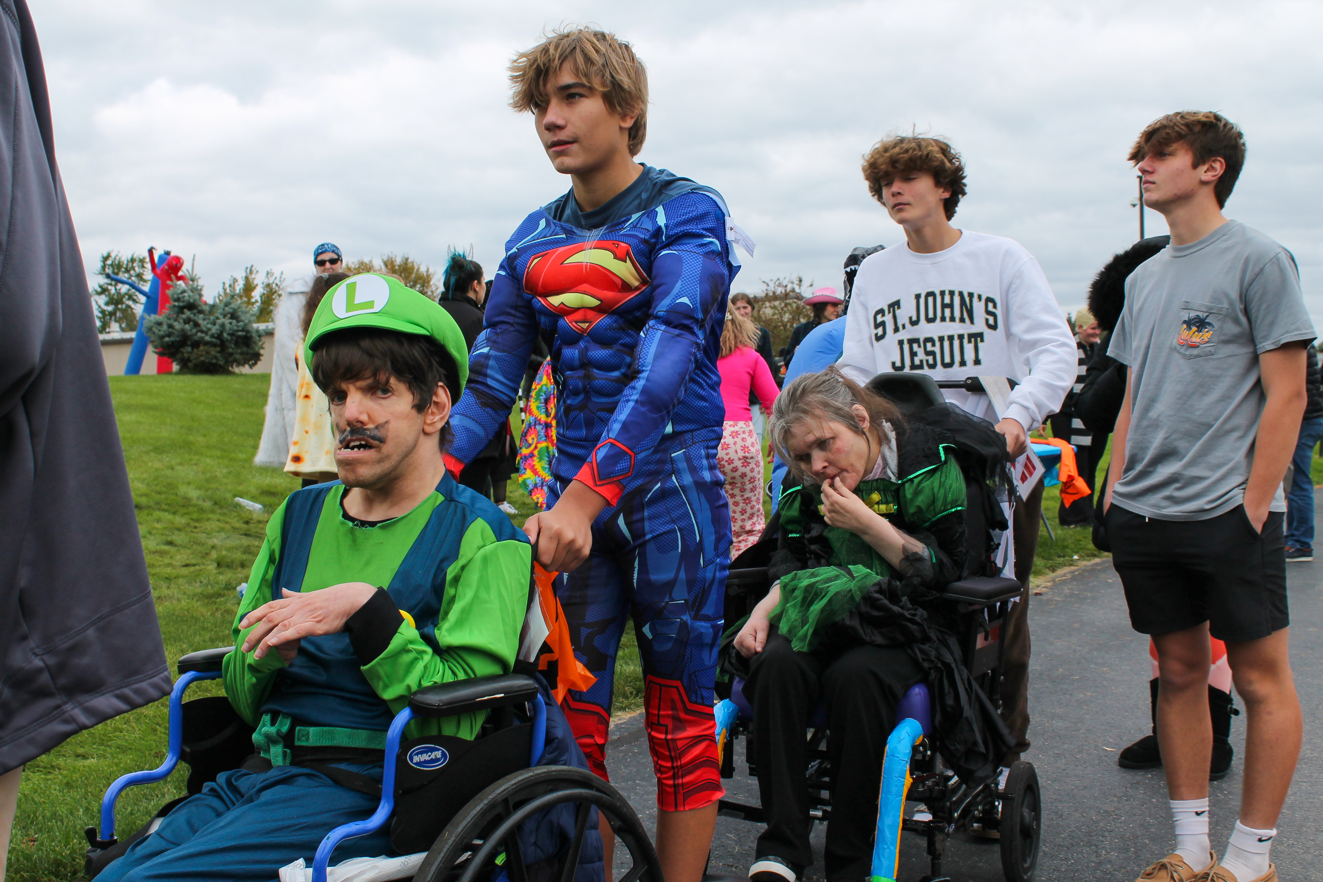 Everyone in costumes, smiling and looking for candy, including a group of people in wheelchairs others are standing 