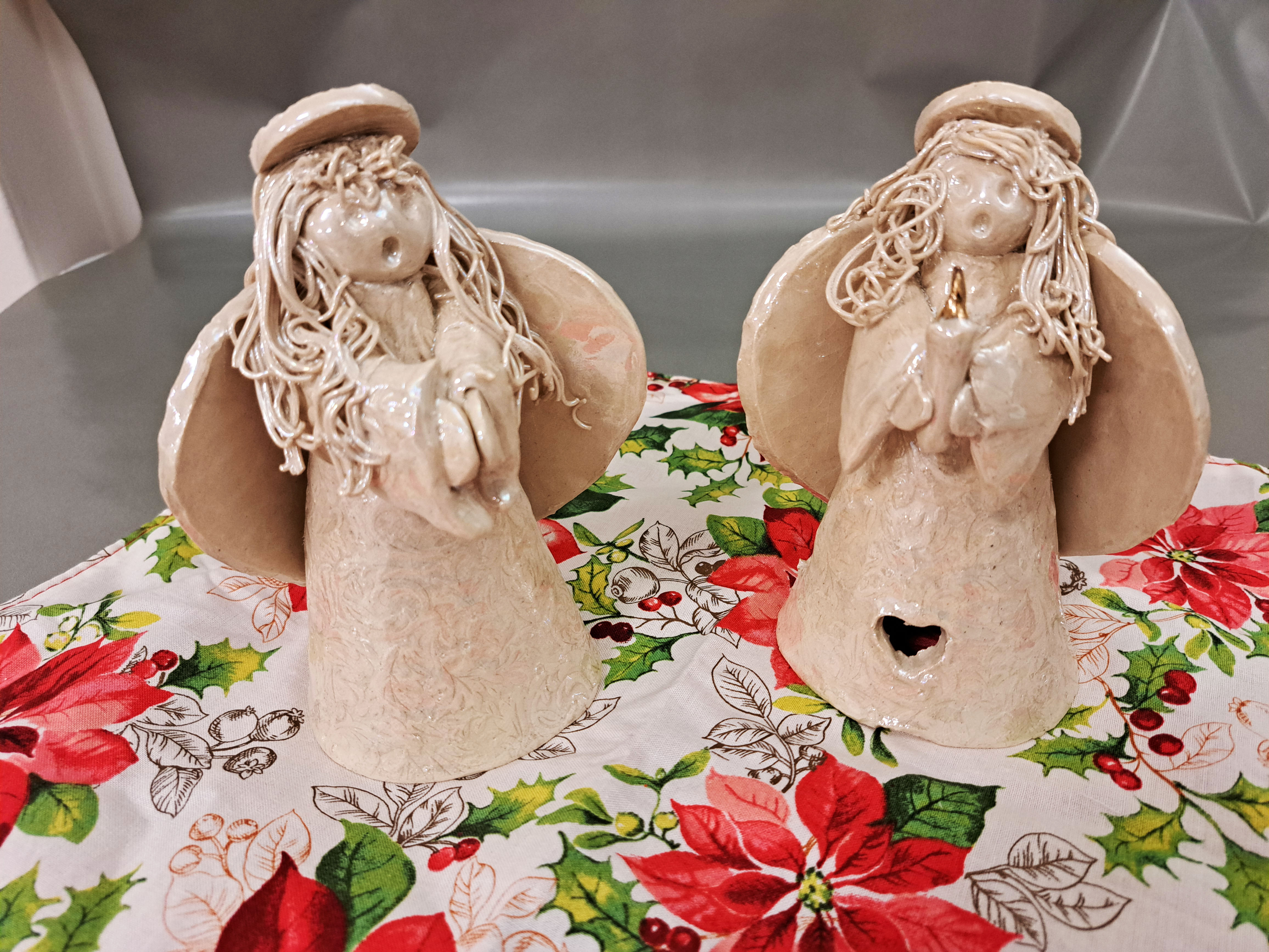 Two ceramic angels gracefully positioned on a table, showcasing intricate details and a serene presence.