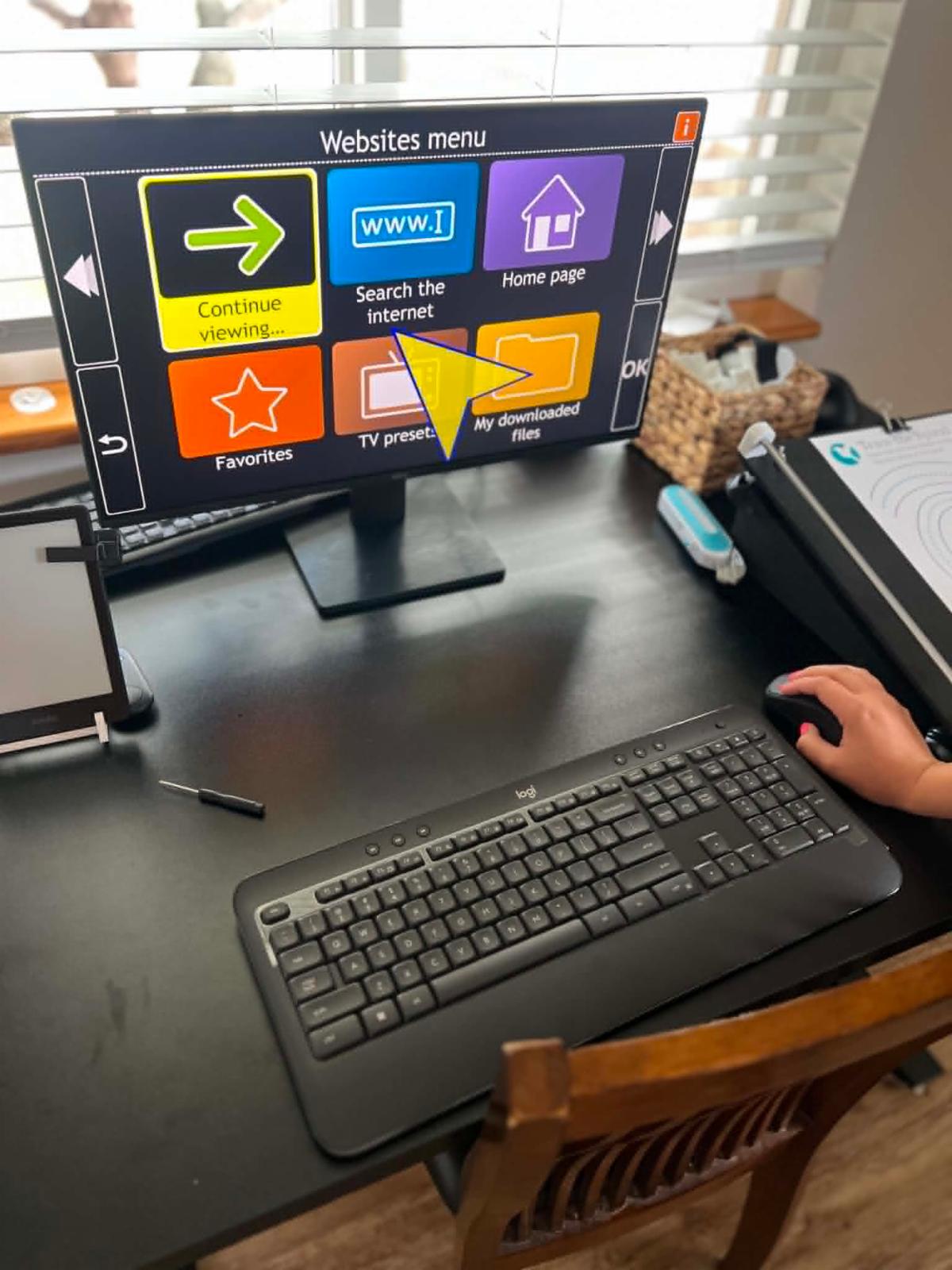ndividual using an accessible computer workstation with adaptive technology and a simplified visual navigation interface to support independent communication and internet access.