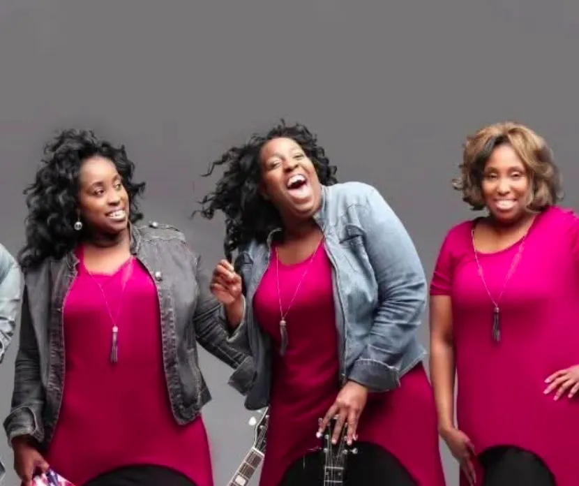 Promotional photo of Nikki D and the Sisters of Thunder, a five-member band smiling with guitars, performing at the Sounds of Sunshine Concert Series at Sunshine Communities.