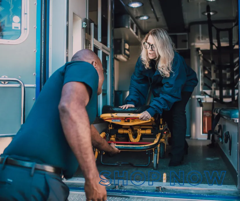 Two emergency medical professionals participate in hands-on stretcher simulation training inside an ambulance during a clinical education experience at Sunshine Communities.