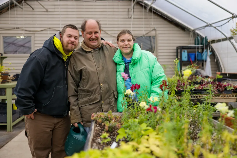 Three people smiling in a greenhouse