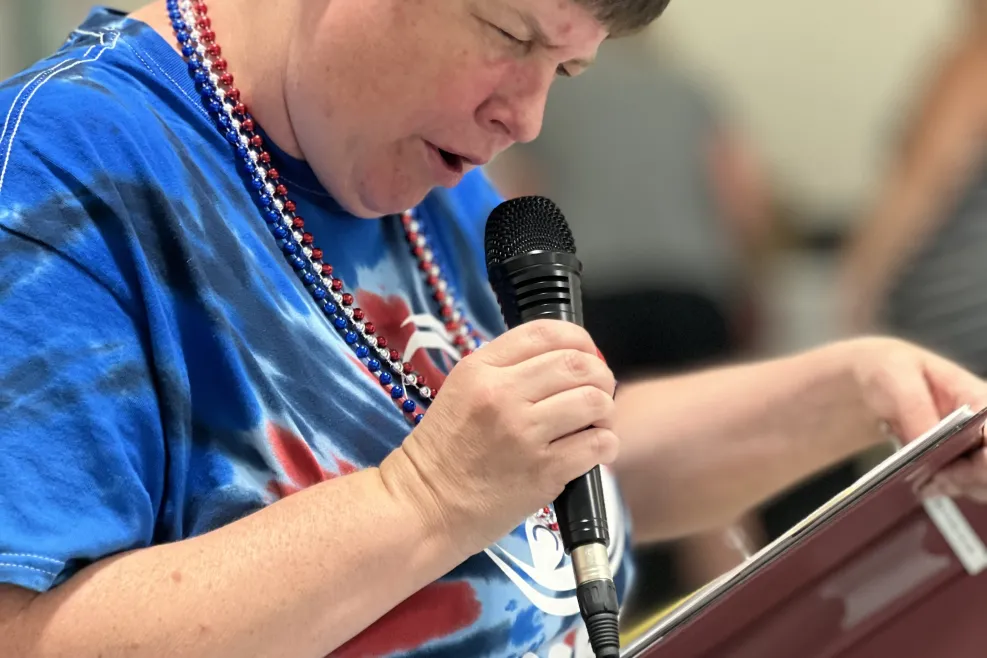 Aktion Club member from Sunshine Communities speaking into a microphone during a community service meeting in Northwest Ohio