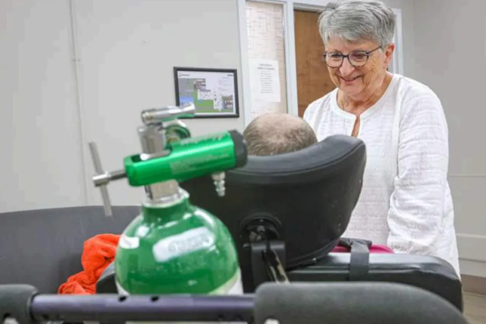 Linda Dittman smiles while caring for an individual supported by Sunshine Communities, with medical oxygen equipment visible in the foreground at the Maumee campus.