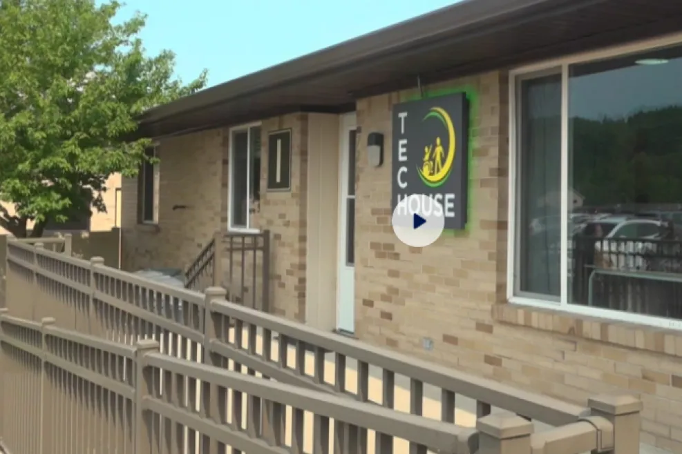Exterior view of Sunshine Communities' Tech House, featuring an accessible entrance with a ramp, a Tech House sign, and the front of the building before entering for a tour.