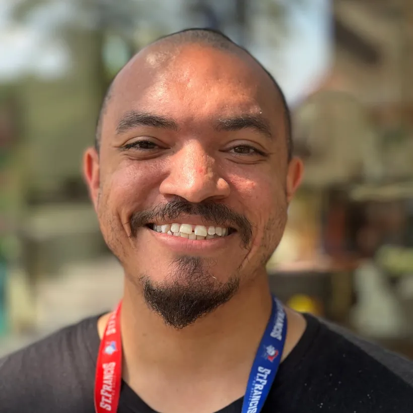 Smiling man wearing a black shirt and lanyard standing outside in sunny weather near Sunshine Communities in Maumee, Ohio.