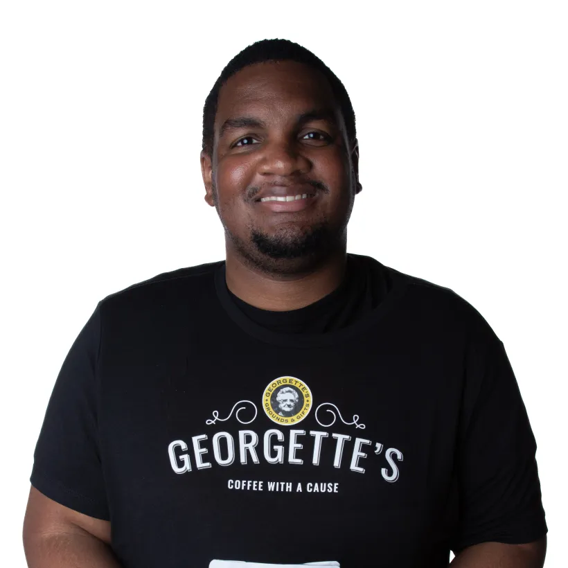 Smiling Georgette’s employee holding a bag of Georgette’s Sunrise coffee, a coffee with a cause supporting people with developmental disabilities.