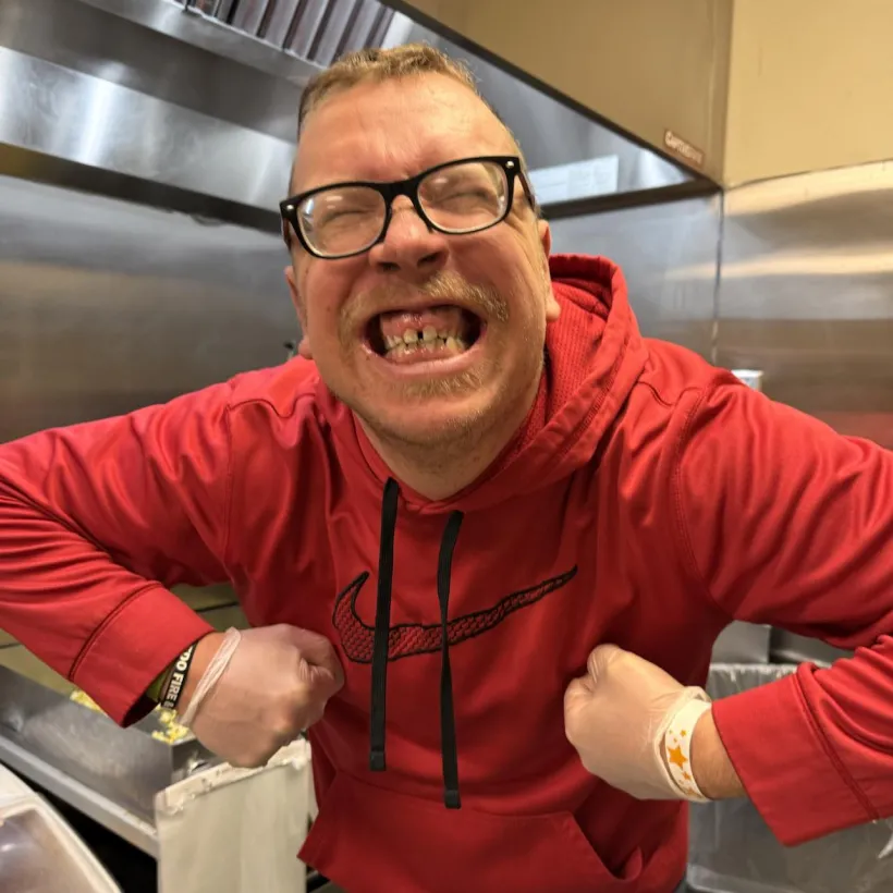 Kelvin Mayti smiling widely while standing in a kitchen